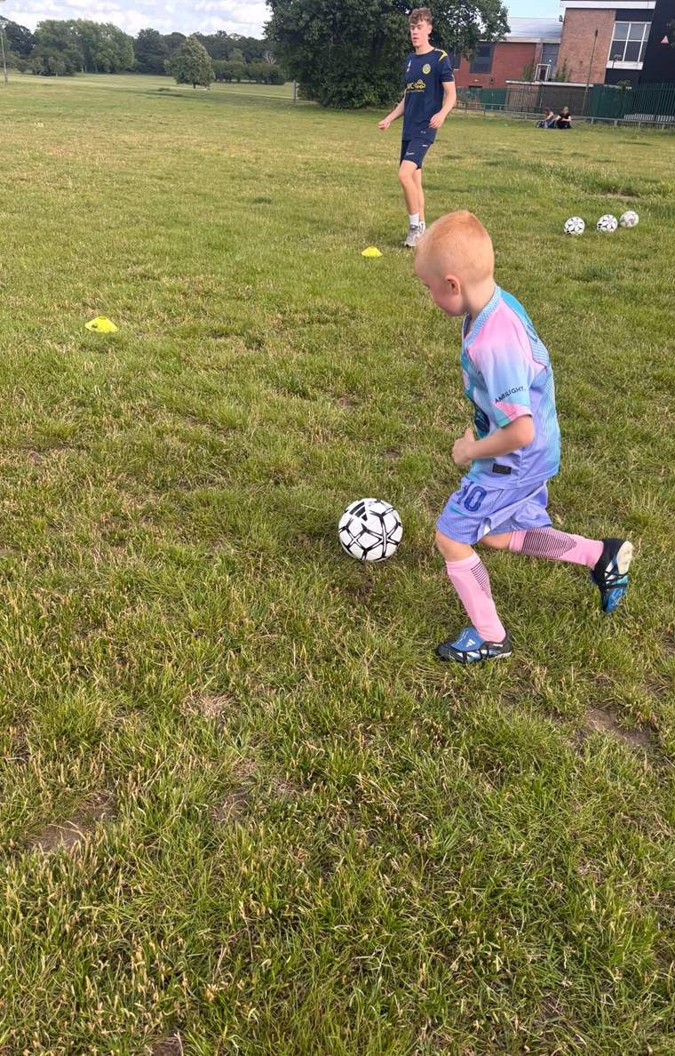 A young player dribbling a ball during a JB Football training session